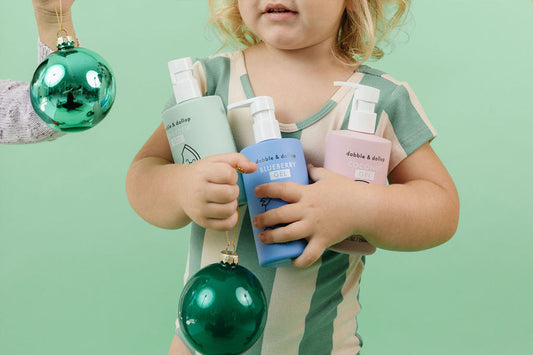 Little girl holding Dabble & Dollop bottles and green ornaments