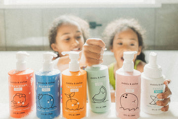 Girls in bath tub with Dabble & Dollop Rainbow of Bubbles