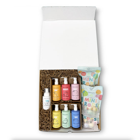 The Dabble & Dollop Limited Edition Target Launch Bundle features six colorful bottles, one spray bottle, and two packs of Mini Drops candy arranged on brown paper filler inside a white gift box.