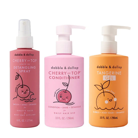 Three Dabble & Dollop bottles—Detangler, Conditioner (both pink), and Tangerine Gel (orange)—stand side by side. Each features cute fruit cartoons and simple labels.