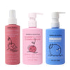 Three colorful bottles of Dabble & Dollop Detangler and Conditioner, plus a blue 2-in-1 body wash-shampoo—all with cute fruit illustrations. From left to right: pink detangler spray, pink conditioner (pump), blue body wash-shampoo.