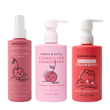 Three pink Dabble & Dollop bottles—Detangler and Conditioner with playful cherry and strawberry art—feature pump or spray tops for easy use.