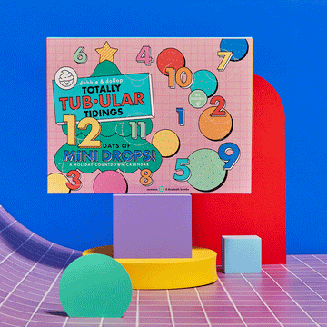 The Dabble & Dollop Totally Tub-ular Tidings Hot Chocolate Soak is a colorful, kid-friendly holiday countdown calendar with numbers 1 to 12, featuring fun bath bombs inside and festive pink and blue packaging.