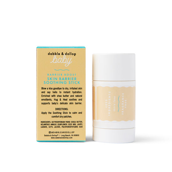 A Dabble & Dollop Barrier Boost Skin Barrier Soothing Stick is placed beside its box. Both are white with teal and yellow labels displaying the product name, brand, and instructions for use.