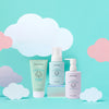Three pastel-colored bottles of Dabble & Dollop’s Baby Bath to Bed Gift Set are displayed against a light blue background with white and pink paper clouds. This set features lotion, hair & body wash, and bubble bath—all specially formulated for sensitive baby skin.