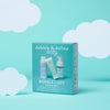 A teal box labeled "Dabble & Dollop Bundle of Joy Minis Kit" displays three travel-size baby care products on a turquoise background with white cloud illustrations.