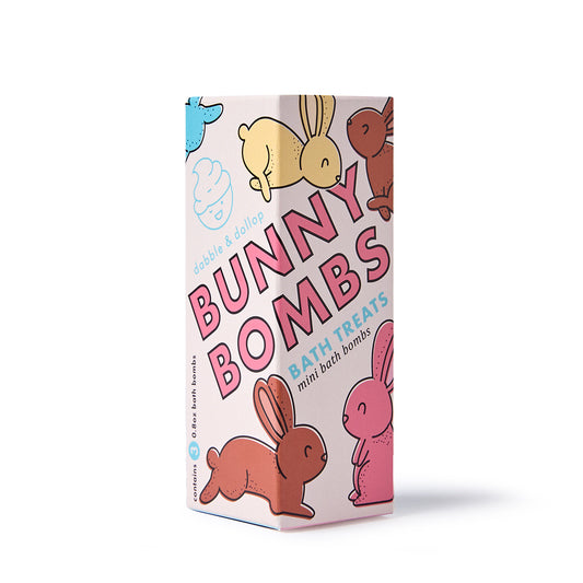 A pastel-colored box labeled Dabble & Dollop Bunny Bath Bomb Trio features playful bunnies and bubbles on a white background—perfect as Easter basket fillers or fun bath treats for kids.