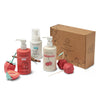 The Cherry Berry Conditioner & Bath Bundle by Dabble & Dollop features colorful, plant-based products like Strawberry and Vanilla Whip Shampoo, displayed with paper fruit decor and a branded brown box.