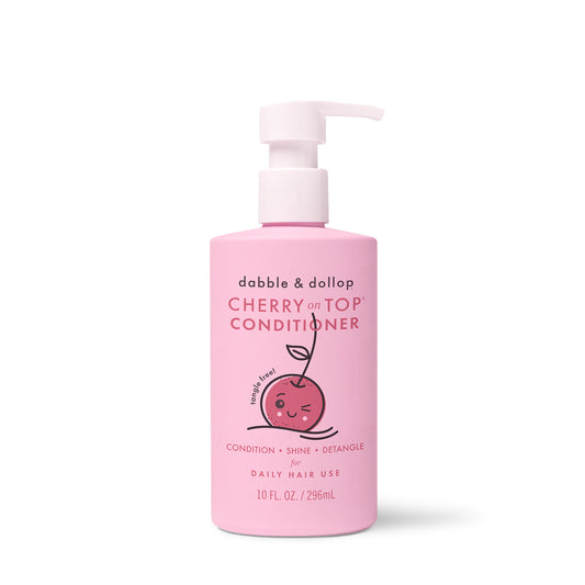 A pink bottle of Dabble & Dollop Cherry on Top® Hair Conditioner with a pump, cute smiling cherry illustration, and text highlighting detangling benefits and a 10 fl oz (296 mL) size.