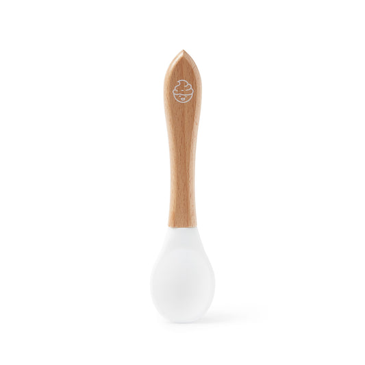 The Dabble & Dollop Mixing Spoon Bath Toy features a natural wood handle and white silicone tip, shown upright on a white background—ideal as a gentle silicone mixing spoon for babies.