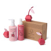 Dabble & Dollop’s Cherry on Top® Detangling Duo Bundle in pink bottles sits beside a brown branded box, with cherry-shaped accents nearby to highlight an easy, tangle-free hair experience for kids.