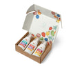 An open box of Dabble & Dollop Bath Gift Sets features three bottles labeled Dole Whip in strawberry, mango, and pineapple scents. Colorful fruit illustrations decorate the inside lid, making it ideal for gifting. Each bottle contains gentle shampoo formulas specially designed for sensitive skin.