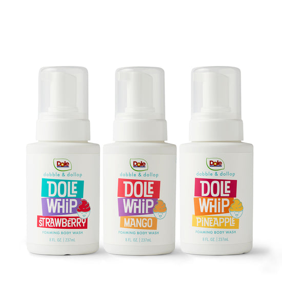 Three bottles of Dabble & Dollop's Dole Whip® Foaming Body Wash Bundle—Strawberry, Mango, and Pineapple—are lined up, each with vibrant fruit-themed labels and tropical scents gentle on sensitive skin.