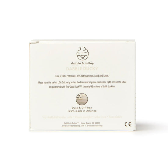 Back view of a Dabble & Dollop Ducky Bath Toy & Teether box. Text highlights the phthalate-free safety features of the duck toy, partnership with The Good Duck™, and its American manufacturing. Company details and social media handles are visible.