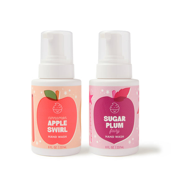 The Dabble & Dollop Sugar, Spice & Suds Foaming Hand Wash Gift Set includes two 8 fl. oz. bottles—one in Cinnamon Apple Swirl featuring a red apple graphic and the other in Sugar Plum Fairy with a purple plum design. Both come with white pump tops and contain natural origin fragrances, making this set a perfect seasonal gift.