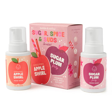 Two Dabble & Dollop Sugar, Spice & Suds Foaming Hand Wash bottles—featuring Cinnamon Apple Swirl and Sugar Plum Fairy scents made with natural origin fragrances—are displayed in front of a pink gift box adorned with matching fruit illustrations and the phrase “Sugar, Spice & Suds So nice!”, creating a charming seasonal gift set.