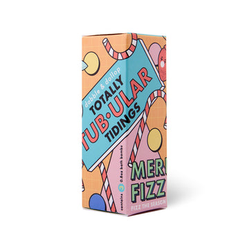 A vibrant rectangular box from Dabble & Dollop, featuring playful festive art, reads “Totally Tub-ular Merry Fizzfest Mini Drops Stocking Stuffer” and “3.8 oz mini bath bombs”—a perfect holiday gift or stocking stuffer.