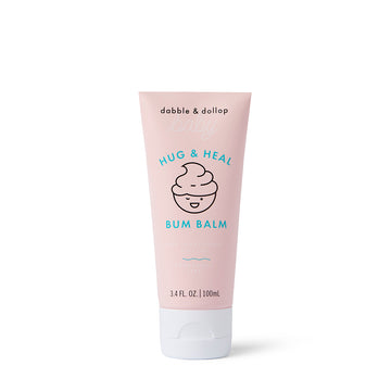 A pink tube of Dabble & Dollop Hug & Heal™ Bum Balm with a smiling swirl icon, zinc oxide for sensitive baby skin, and 3.4 fl. oz. (100 ml), shown on a white background.