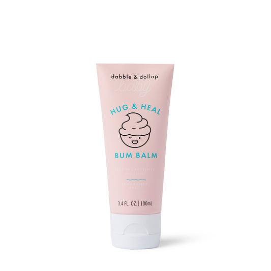 A pink tube of Dabble & Dollop Hug & Heal™ Bum Balm with a smiling swirl icon, zinc oxide for sensitive baby skin, and 3.4 fl. oz. (100 ml), shown on a white background.