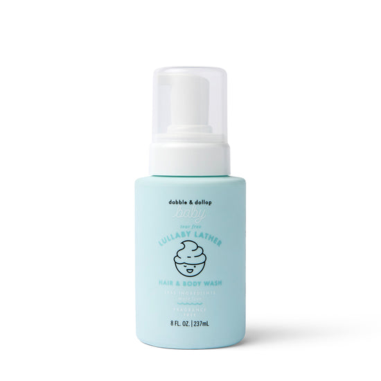 A light blue bottle of Dabble & Dollop Lullaby Lather™ Hair & Body Wash with a white pump, featuring a smiling swirl graphic and product info on the label.