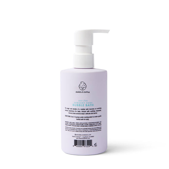 A lavender bottle of Dabble & Dollop Sensory Suds™ Bubble Bath with a white pump top stands upright against a white background, displaying product details and instructions on its label.