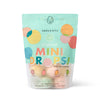A vibrant, resealable pouch labeled “Dabble & Dollop Tropical Mini Bath Bombs” features pastel circles, fruit art, and highlights coconut, guava, mango, and kiwi scents made with natural ingredients for kids' baths.