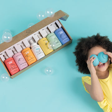 Little girl laying next to Dabble & Dollop Rainbow of Bubble Bath Bundle