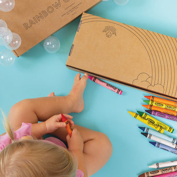 Little girl coloring in Rainbow of Bubbles Bath Bundle box with crayons