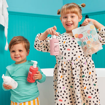 Two children holding assortment of Dabble & Dollop kids bath care products